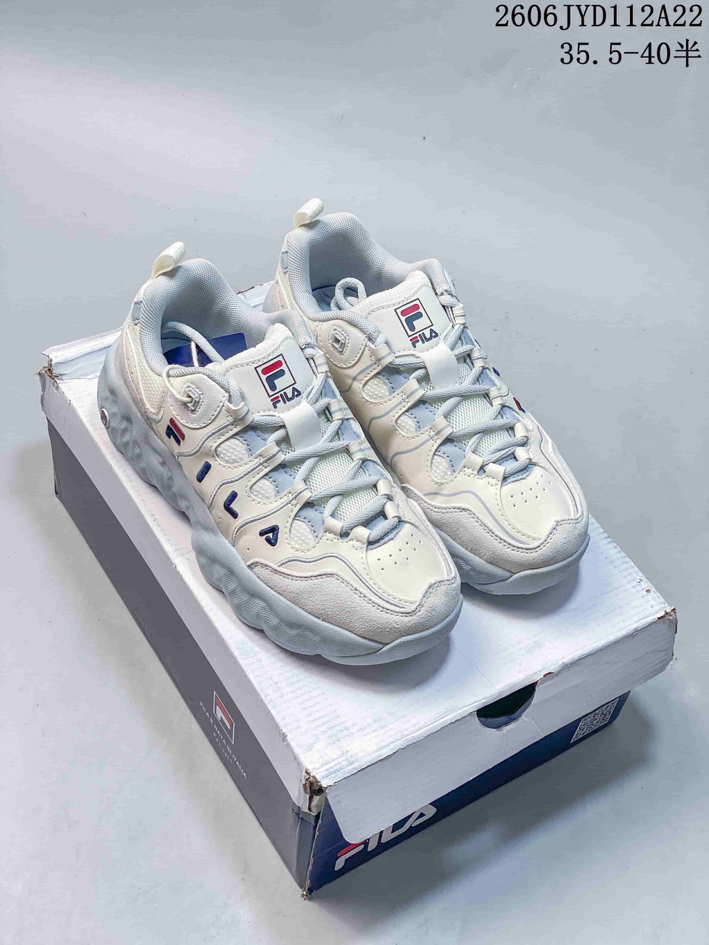 Pair of white and gray FILA Muffin low-top sneakers on a shoe box