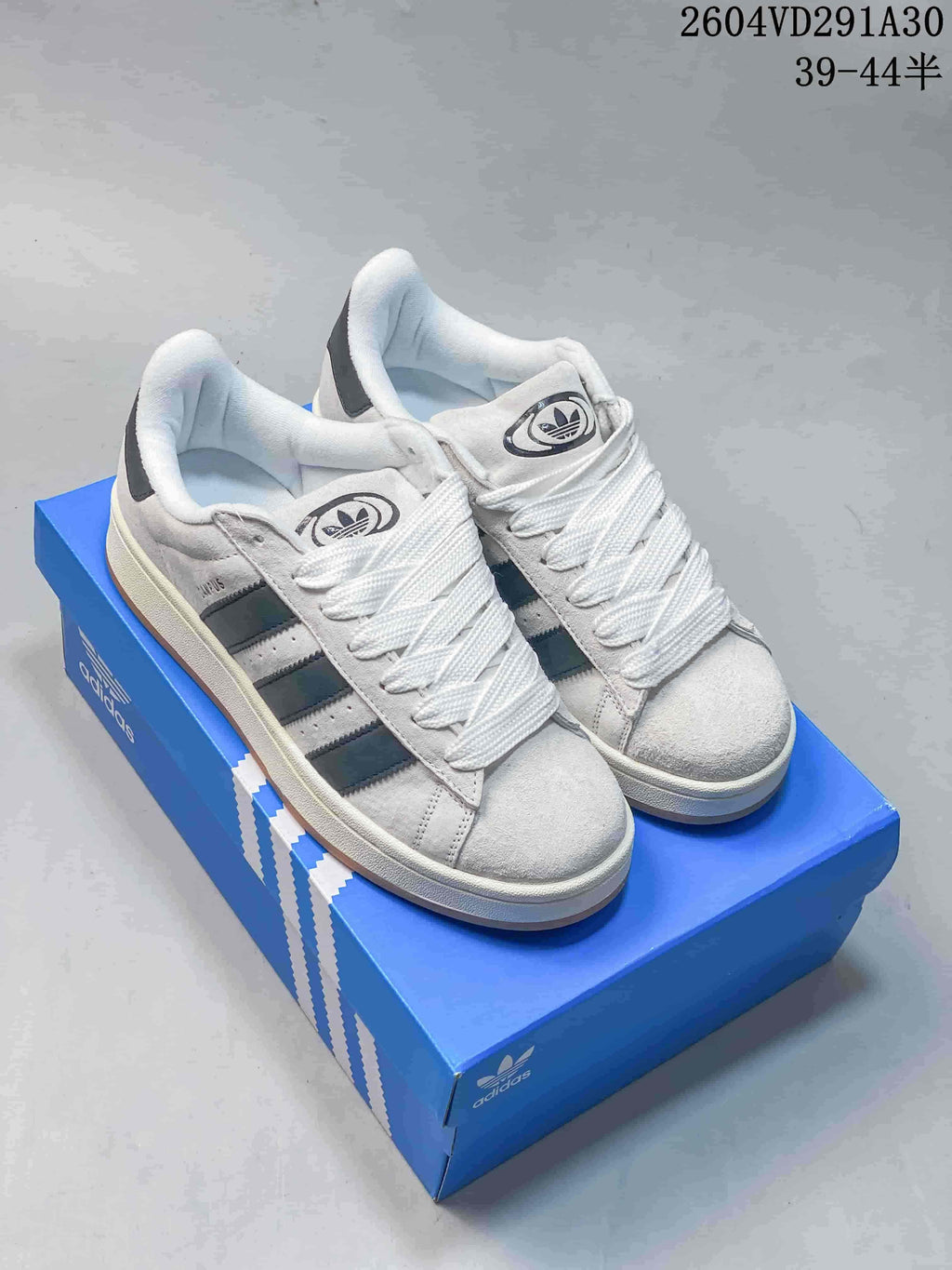 Pair of light grey Adidas Campus sneakers with dark side stripes and white laces.