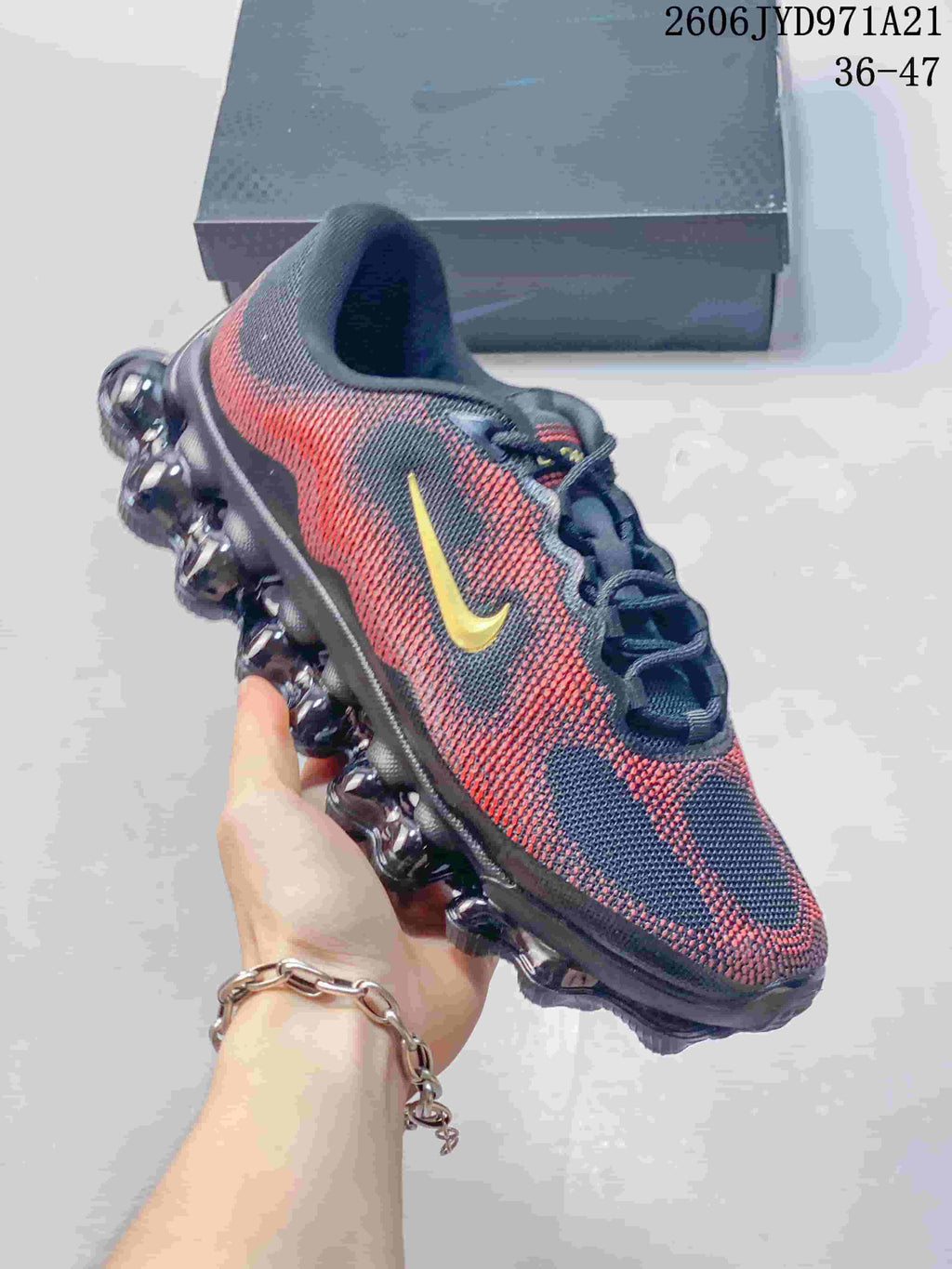 Side view of a patterned navy, red and gold Nike Air Liquid Max shoe with a segmented bubble-like sole; image displays a size range.
