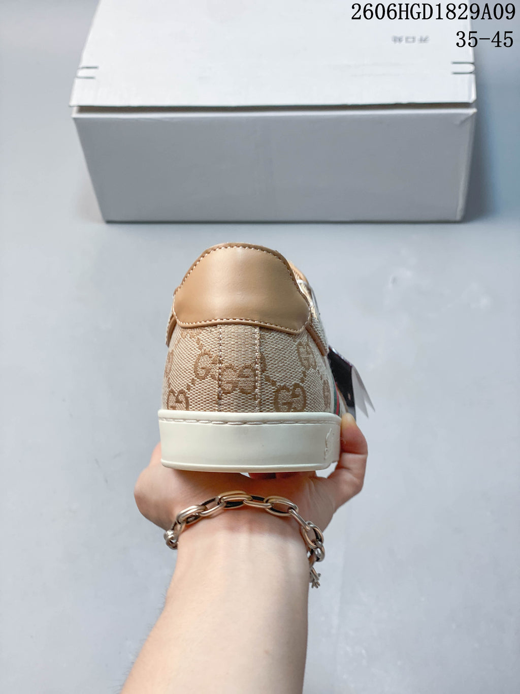 Rear view of a beige GG-pattern sneaker with a tan heel panel