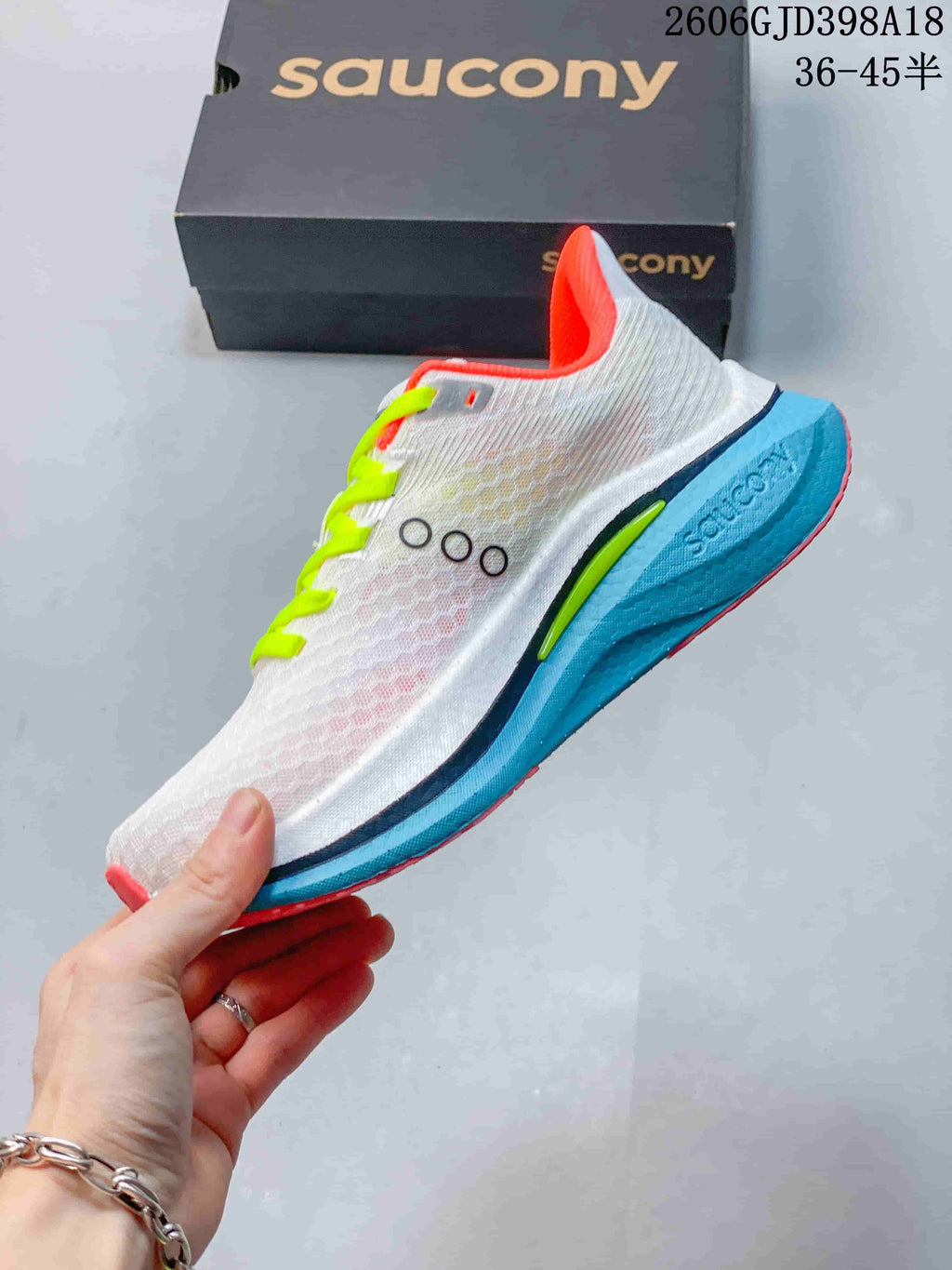 Side view of a white Saucony running shoe with turquoise midsole and coral accents
