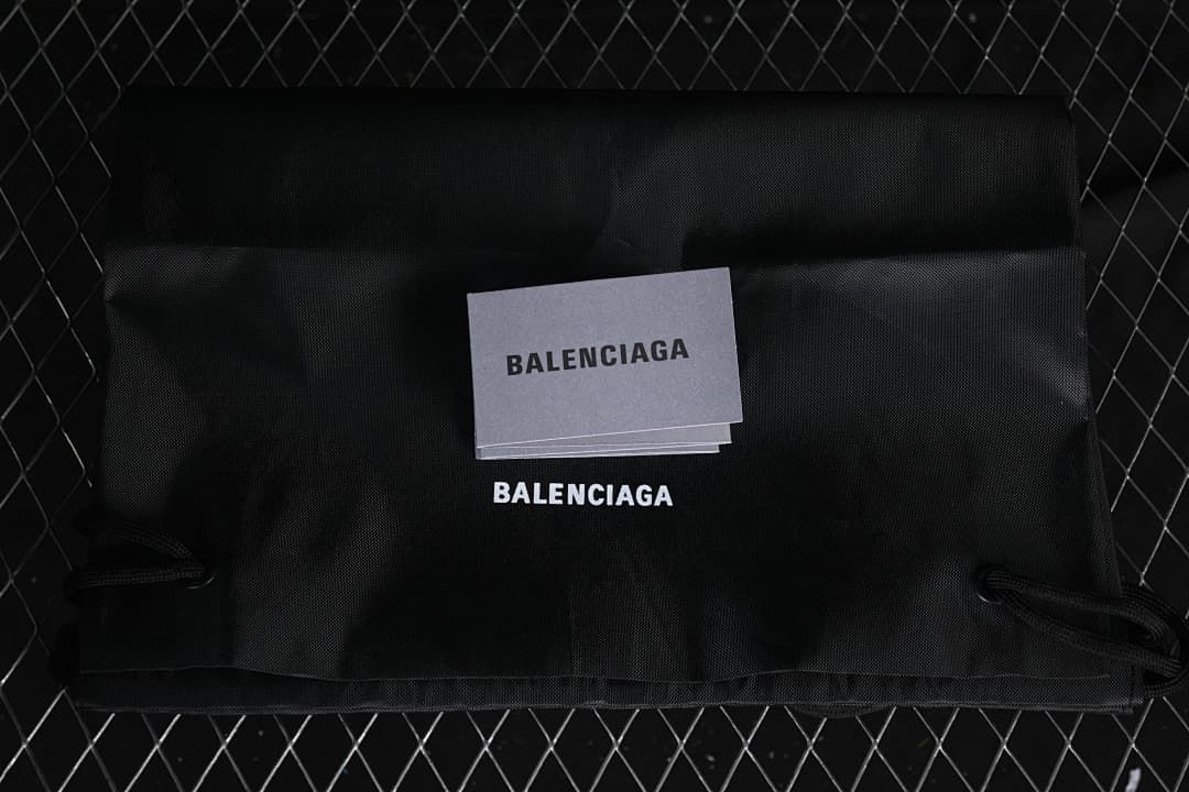 Black Balenciaga dust bag and cards shown with the sneakers
