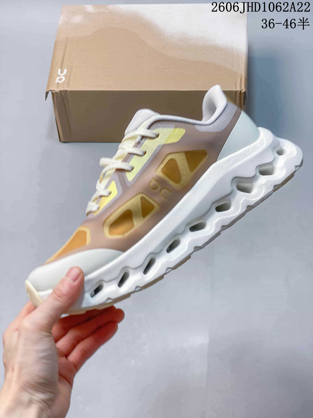 Side view of an On Cloudtilt Remix sneaker with a beige and gold upper and cutout sole.