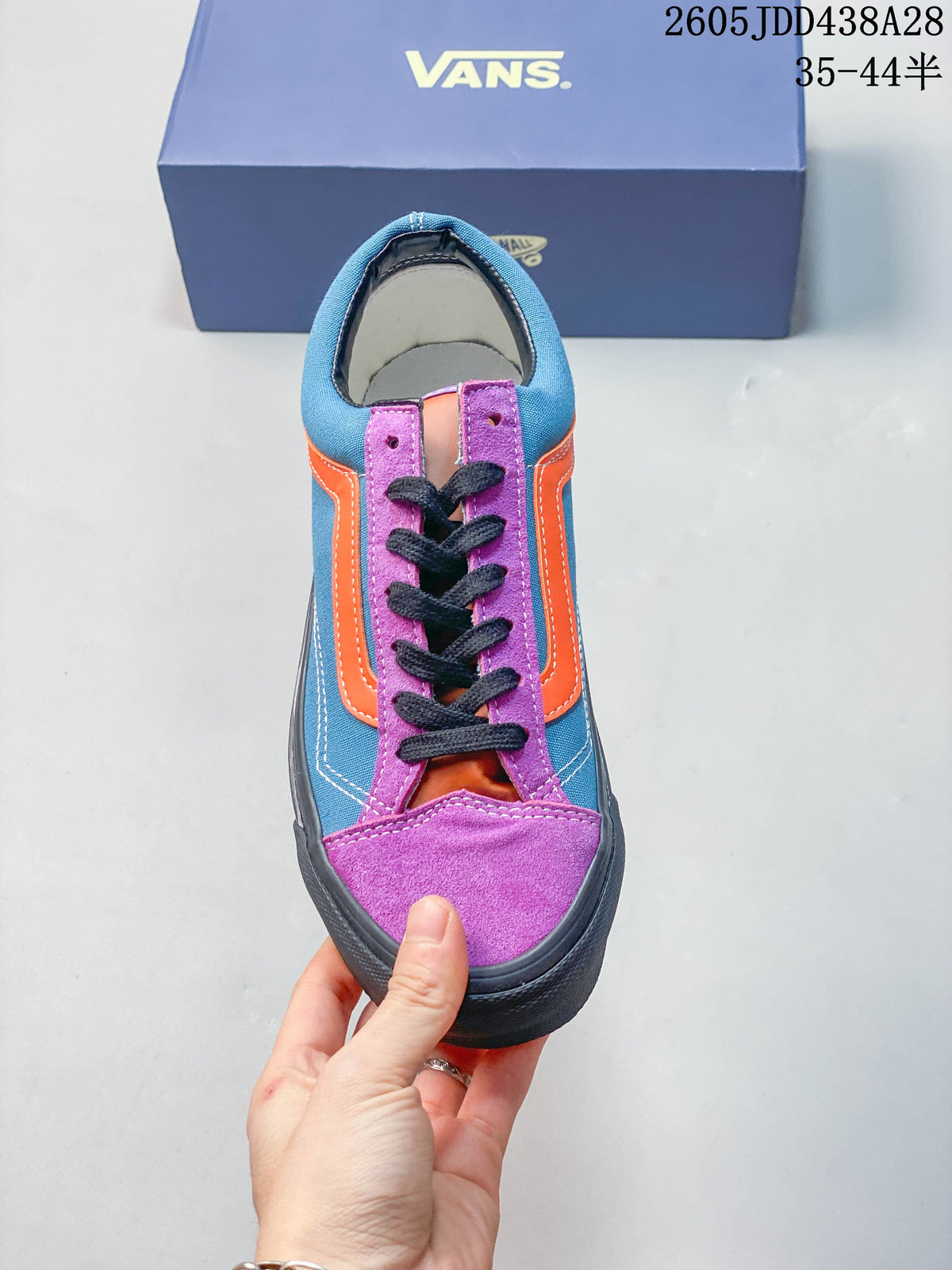 Front view of the sneaker with purple panels, orange accents, and black laces