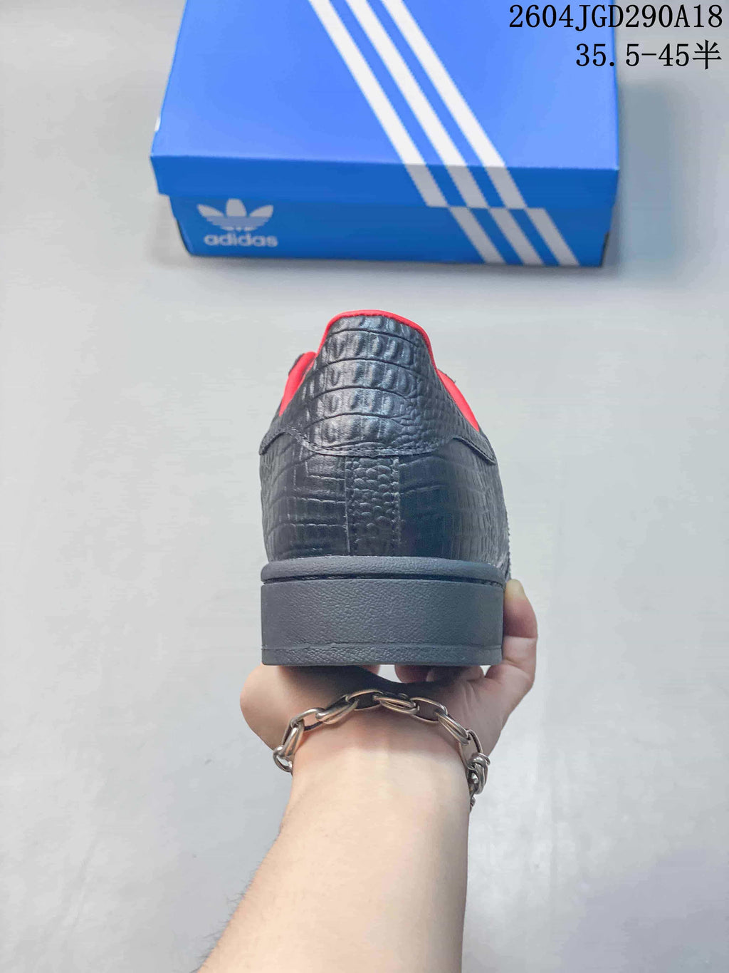 Rear view of a black Superstar 2 sneaker with red collar trim