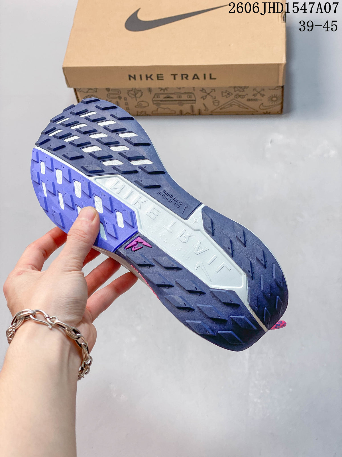 Underside of a Nike ReactX Pegasus Trail 5 shoe showing the lugged outsole in navy, purple, and white.