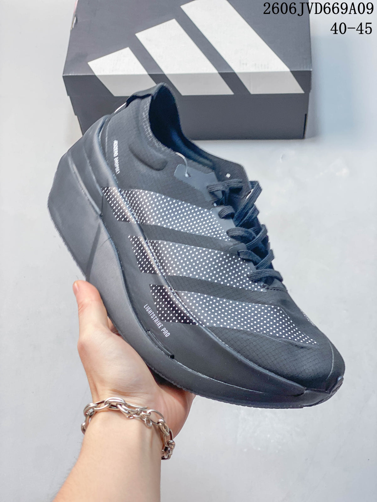 Side view of a dark gray Adidas shoe with dotted stripes and sculpted sole