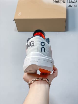 Rear view of a white and coral On Cloudboom Volt shoe with a box marked 36–45.