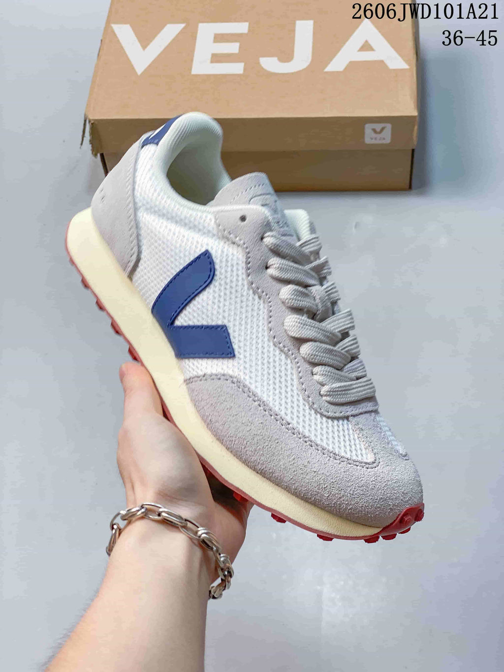 Close side view of the sneaker with a blue V-shaped logo and red outsole