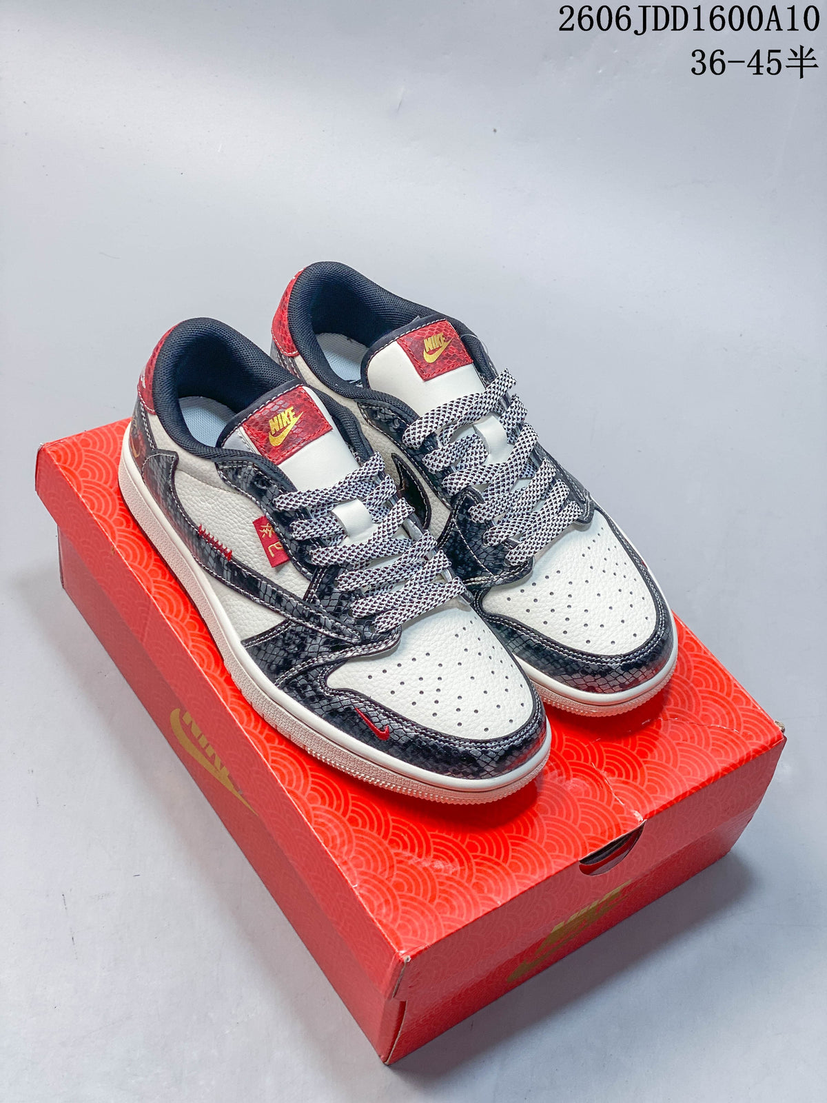 Pair of off-white and dark patterned low-top sneakers with red accents displayed on a red box