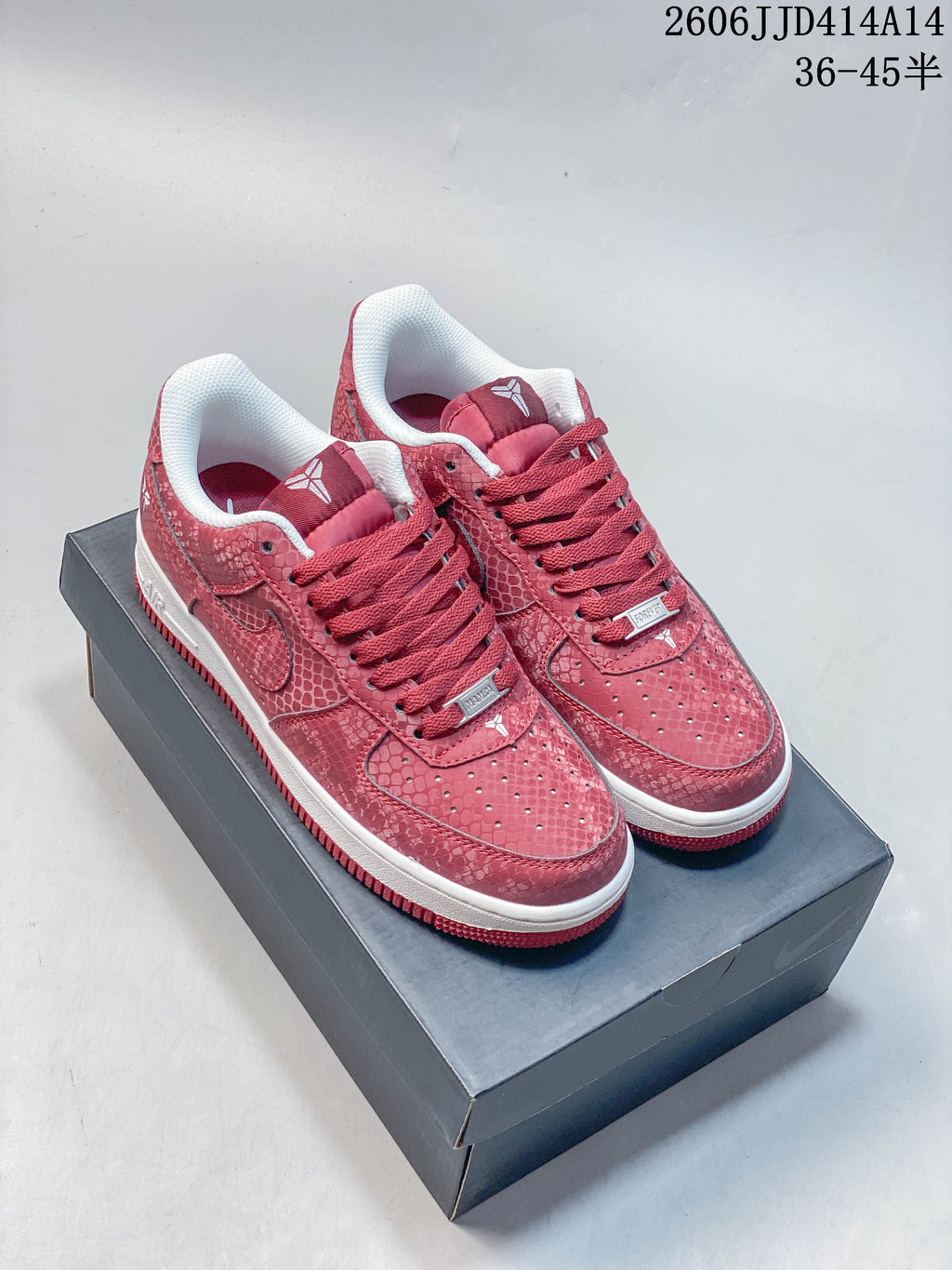 Pair of red patterned low-top sneakers with white midsoles, shown on a shoe box
