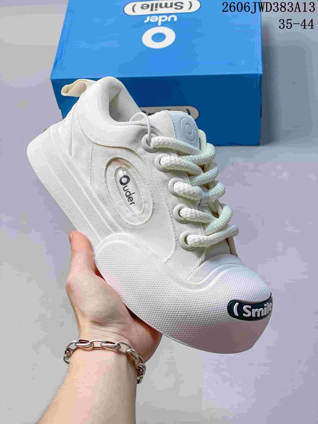 Angled side view of the white sneaker with chunky laces and Smile toe badge