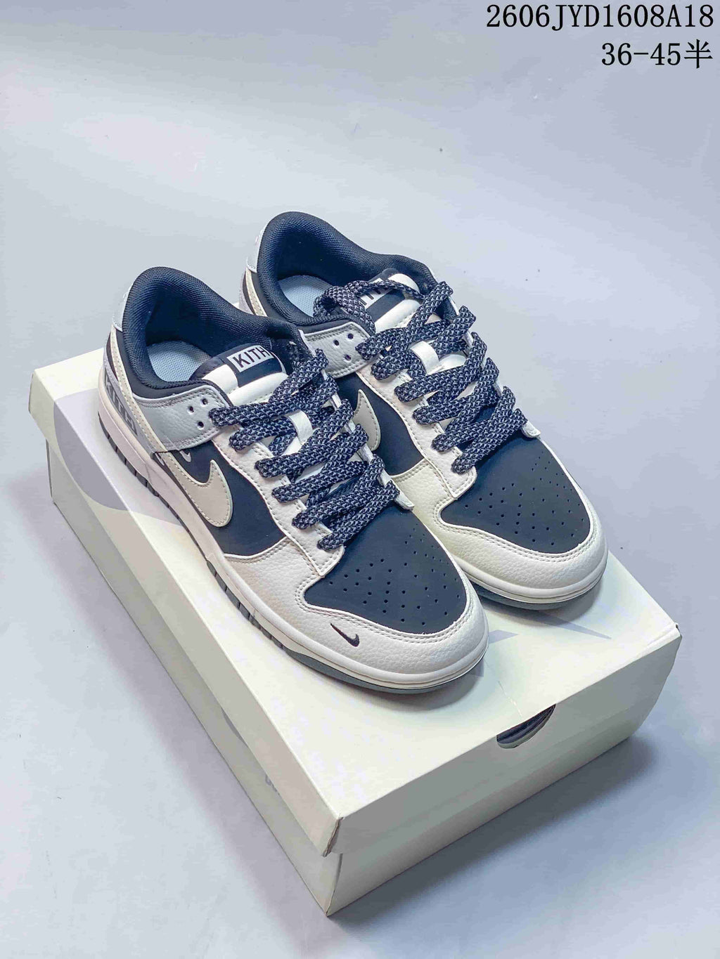Pair of navy, grey, and off-white Nike SB Dunk Low sneakers on a shoe box