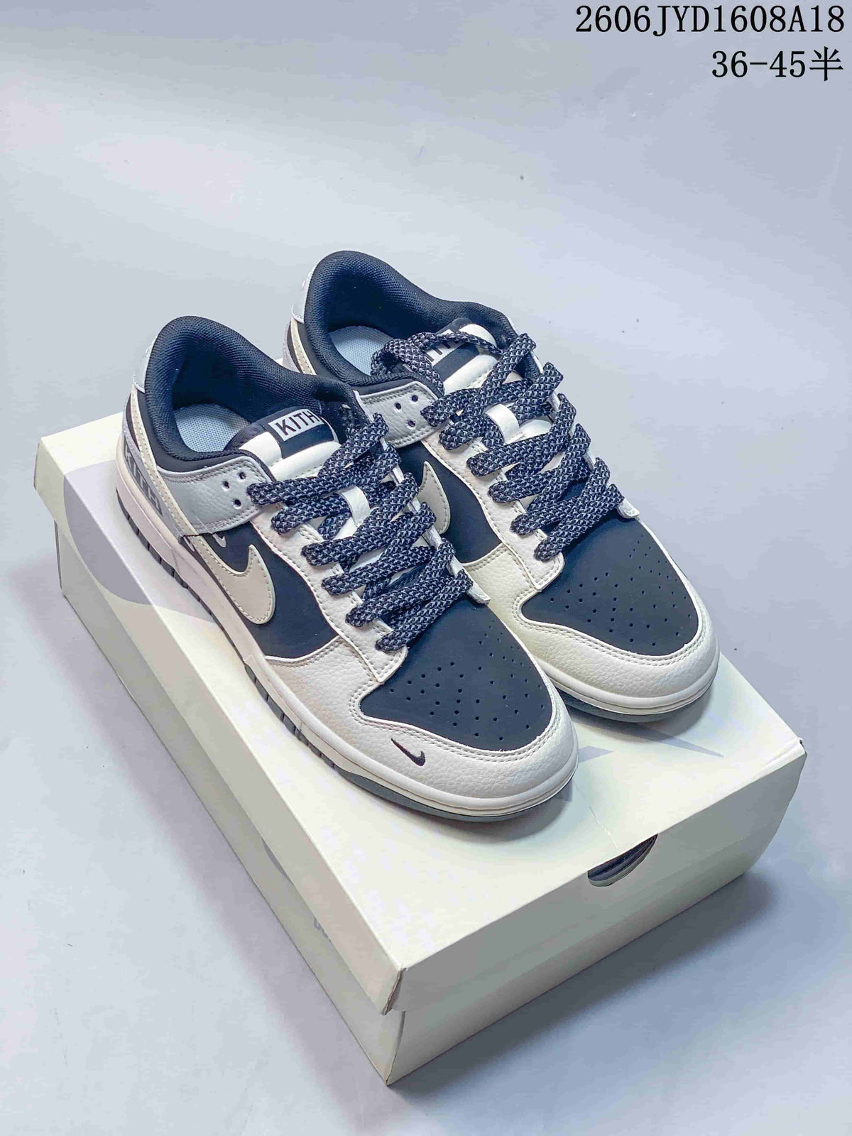 Pair of navy, grey, and off-white Nike SB Dunk Low sneakers on a shoe box