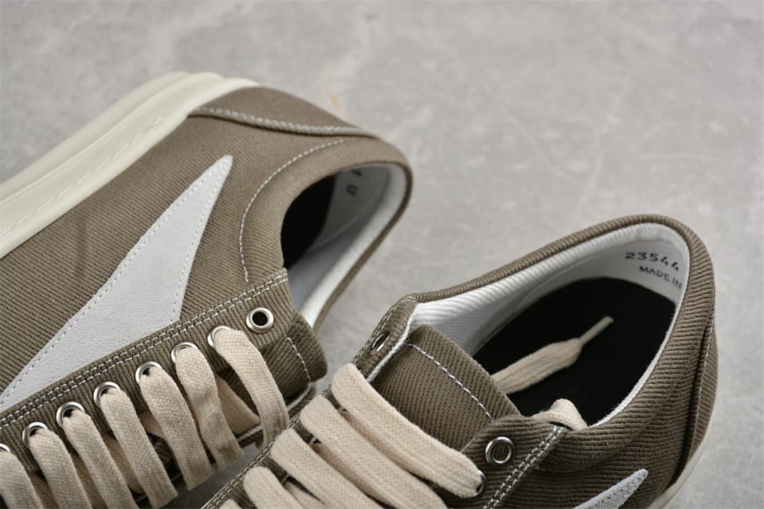 Close-up of brown canvas sneakers showing the laces, metal eyelets, stitching, and light-colored side detail