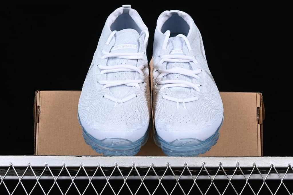 Front view of the pair of white knit sneakers on a box