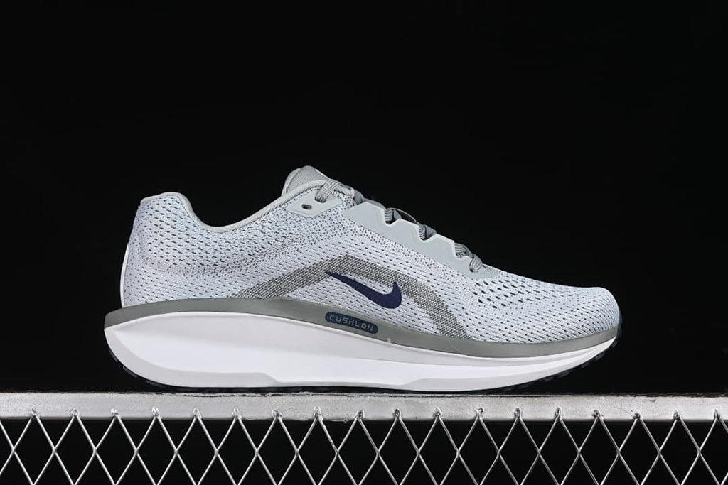 Side profile showing the gray patterned upper, navy Swoosh, and midsole