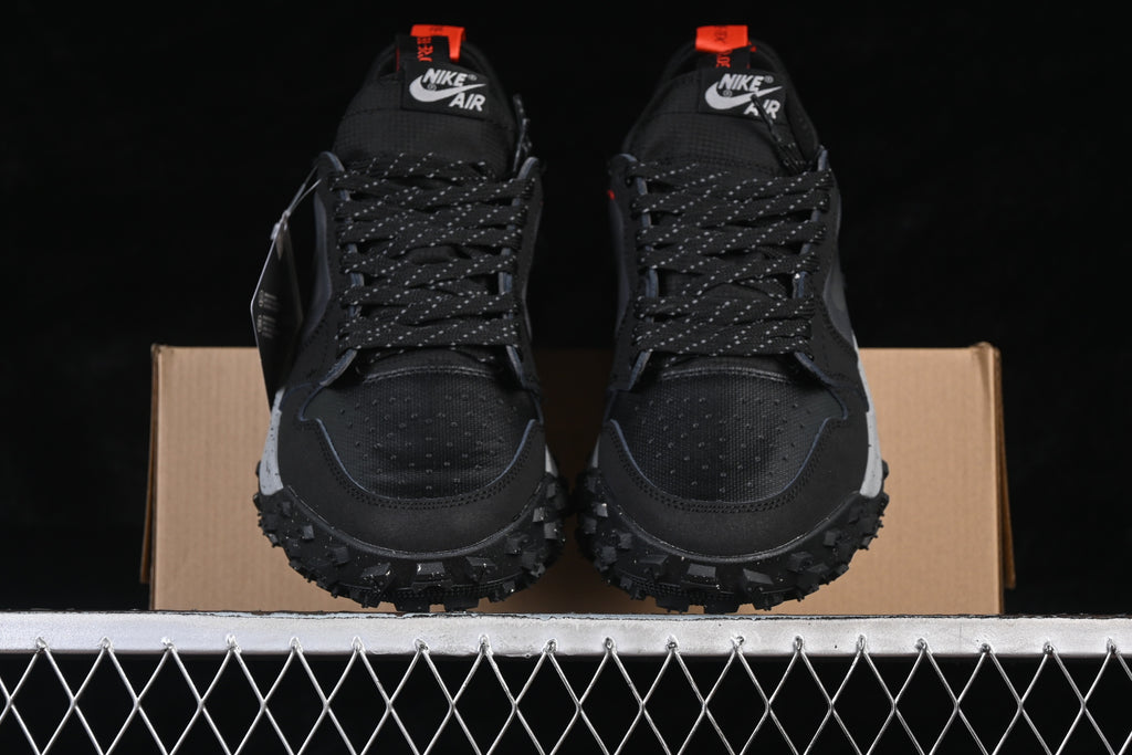 Front view of black and dark gray low-top sneakers with orange accents and rugged soles