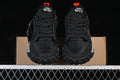 Front view of black and dark gray low-top sneakers with orange accents and rugged soles