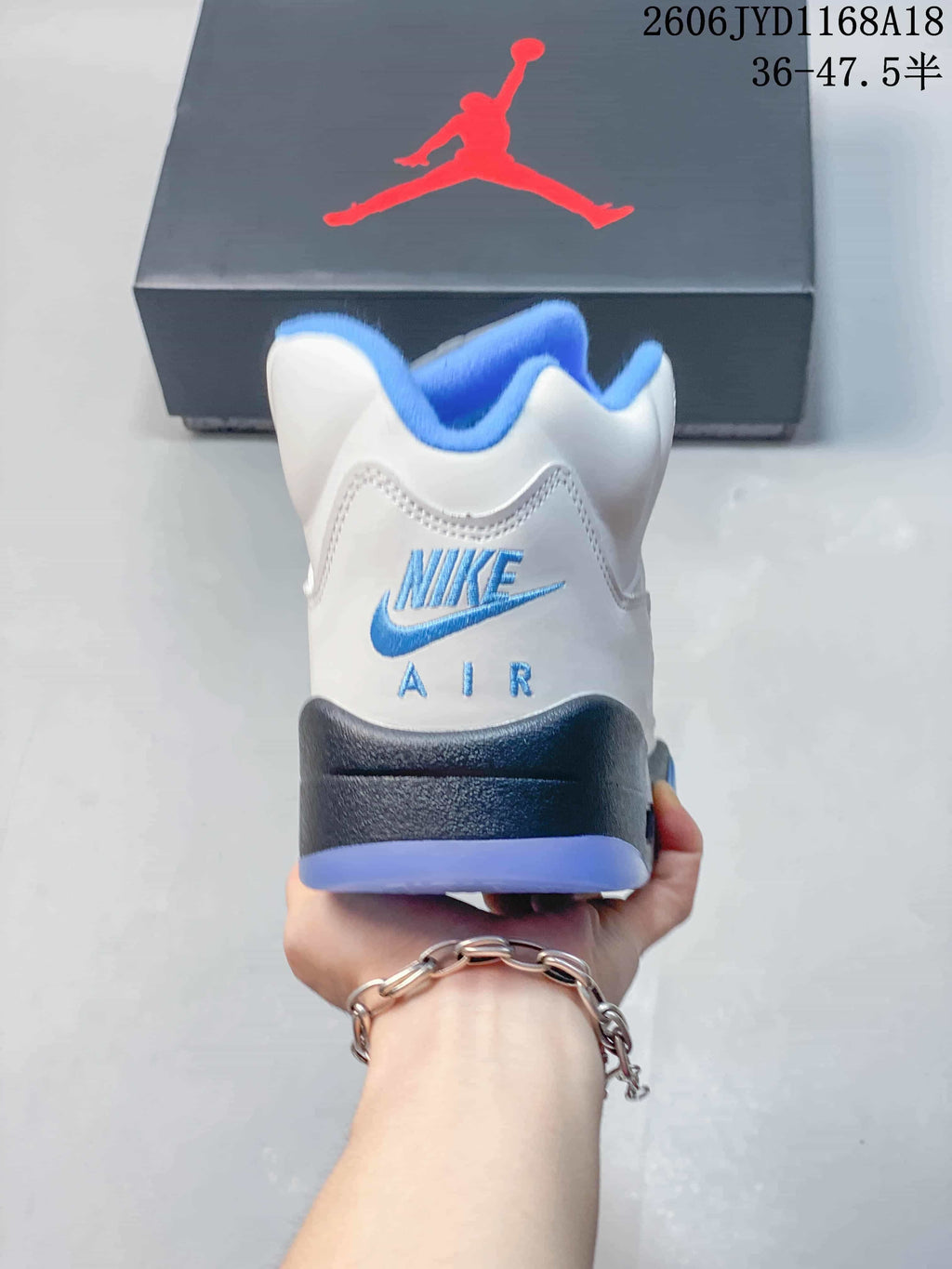 Rear view of a white sneaker with blue branding and gray heel detail