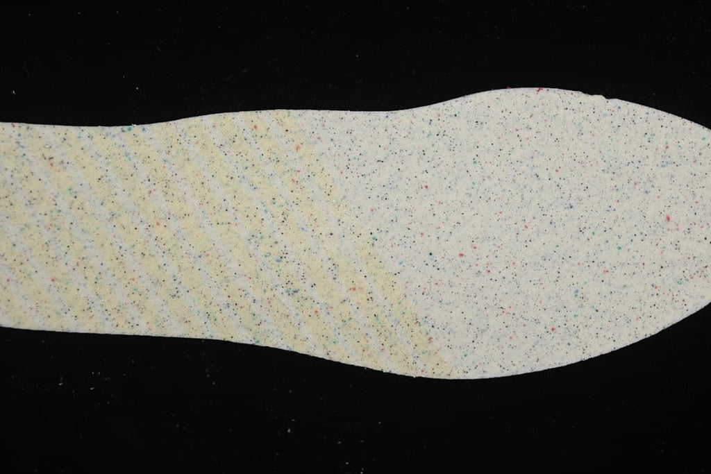 Removable insole shown from the underside with a multicolored speckled surface.