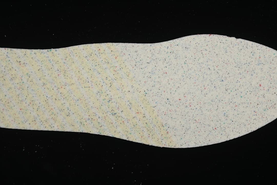 Removable insole shown from the underside with a multicolored speckled surface.