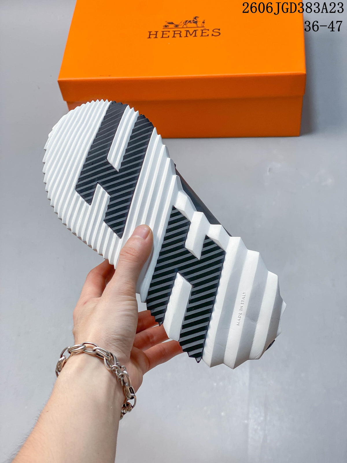 Underside of a sneaker showing a white ridged sole with dark tread sections