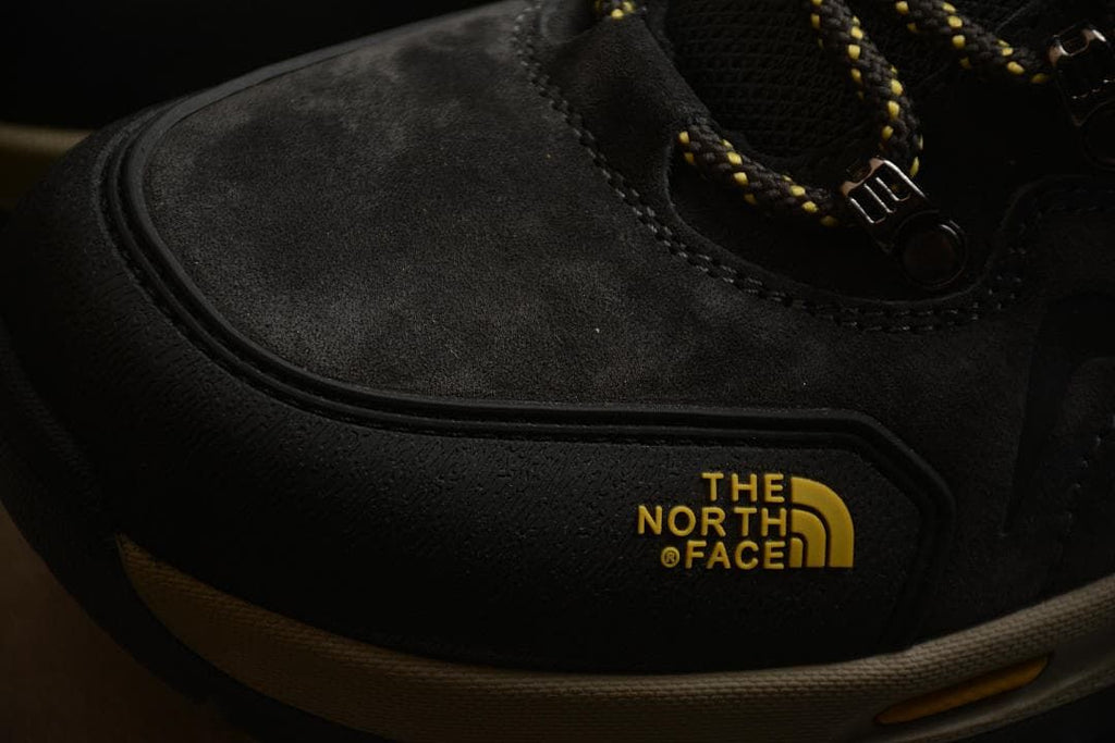 Close-up of the black toe and side panels with yellow The North Face branding.