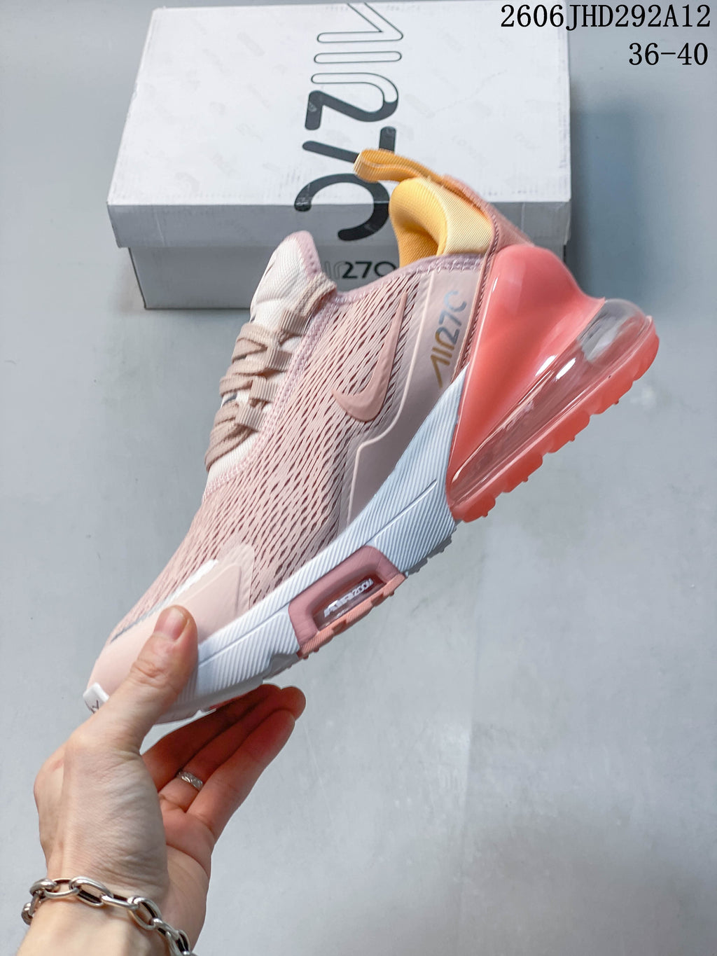 Side view of a pale pink Nike Air Max 270 shoe with a coral heel unit