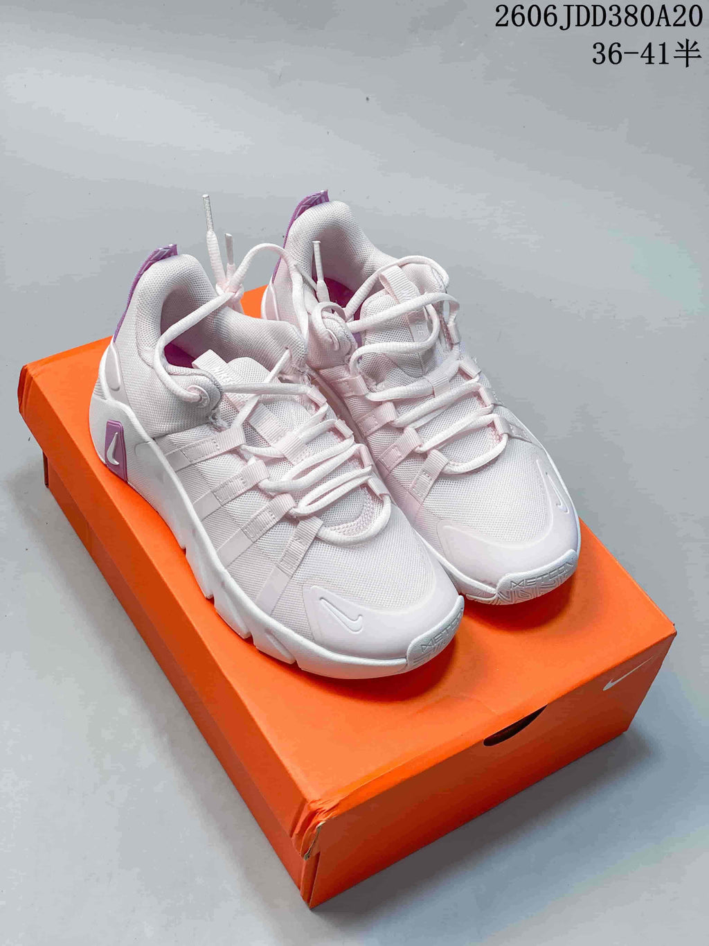 Pair of white Nike Free Metcon 7 training shoes with purple accents on an orange shoebox
