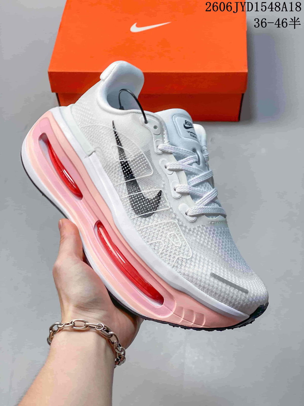 Angled side view showing the white upper, dark side detail, and pink midsole.