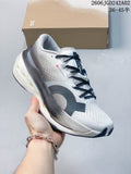 ON Cloudboom Max shoe shown from a side angle in white, gray, and black, with the shoe box behind it.