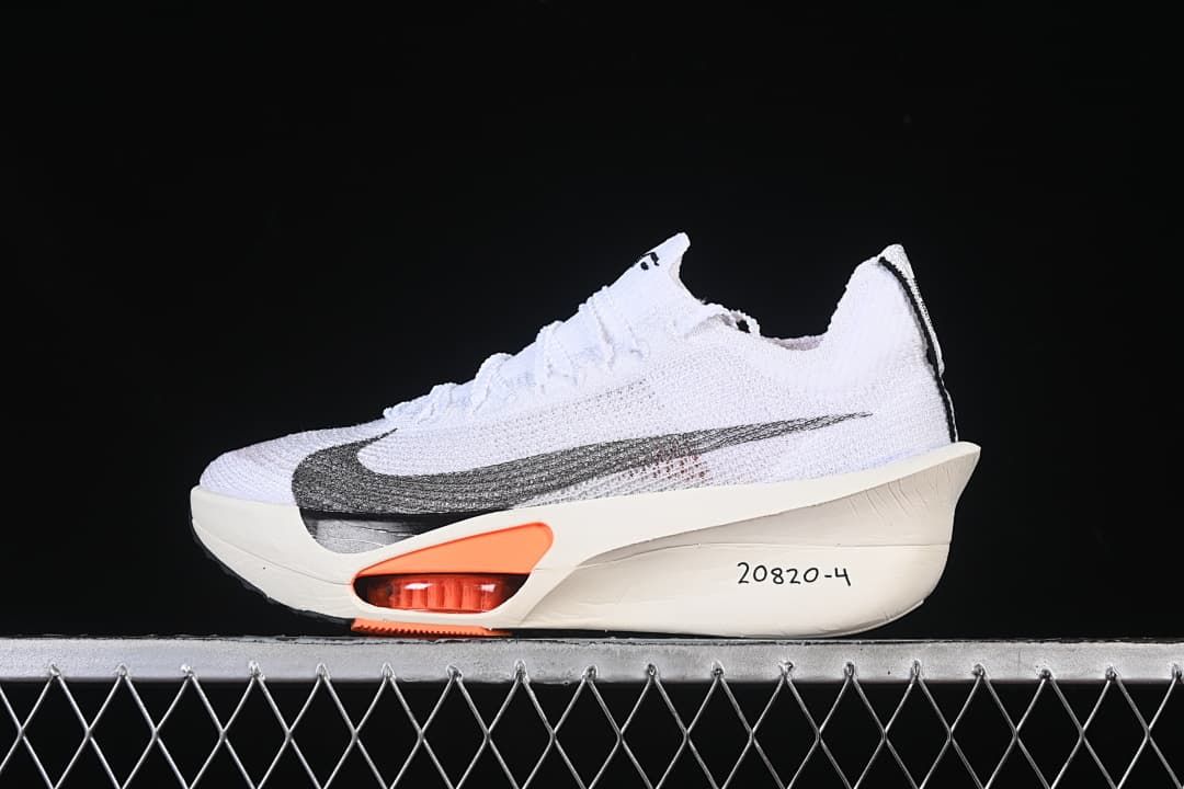 Side view of a white Nike running sneaker with a dark Swoosh, orange sole accents and off-white sole