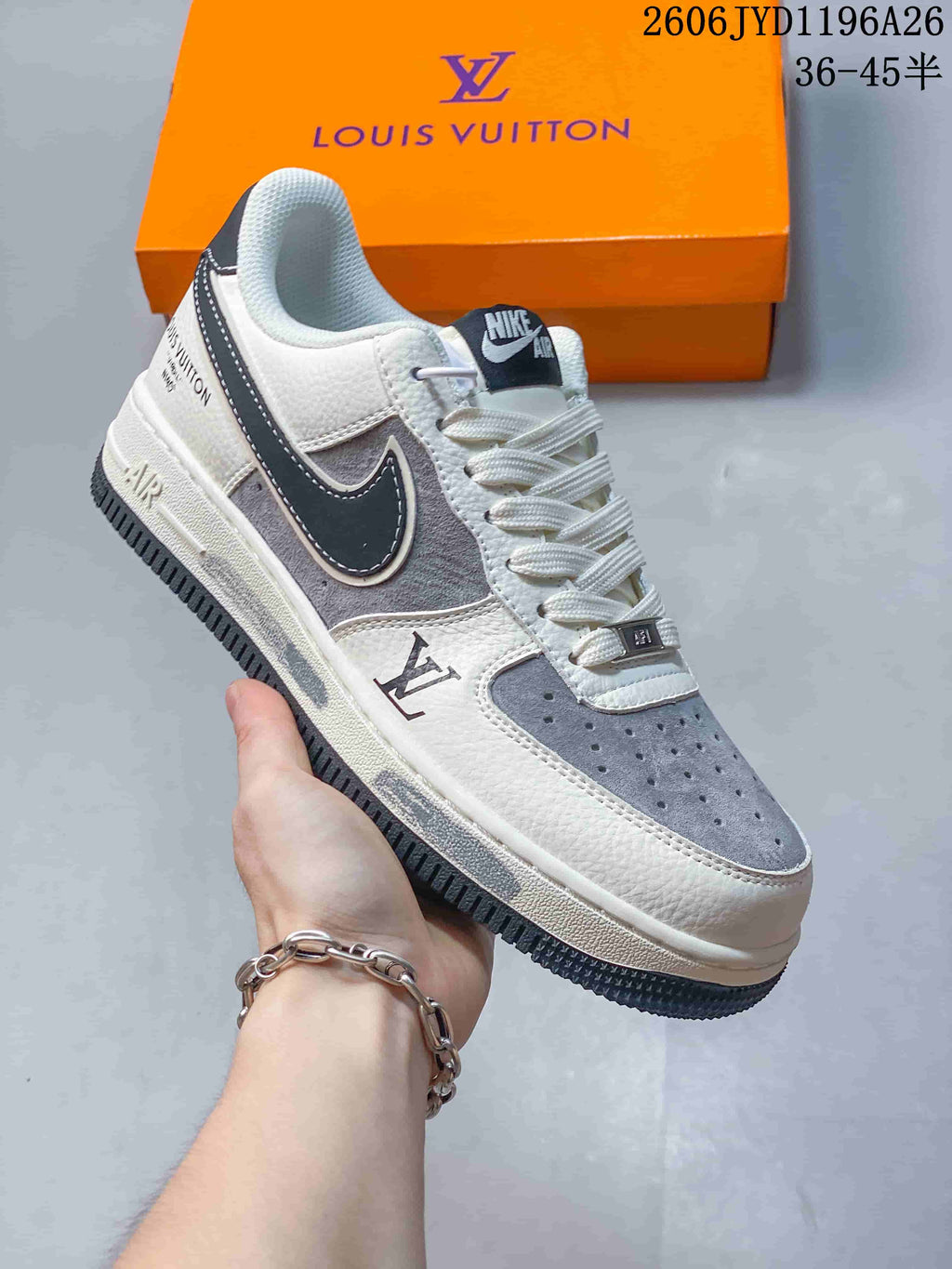 White and gray low-top sneaker with a dark side detail and monogram-style markings, shown close up.