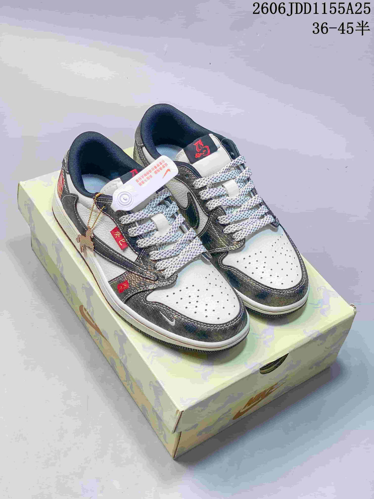 Pair of white and metallic gray Jordan low-top sneakers on a patterned box