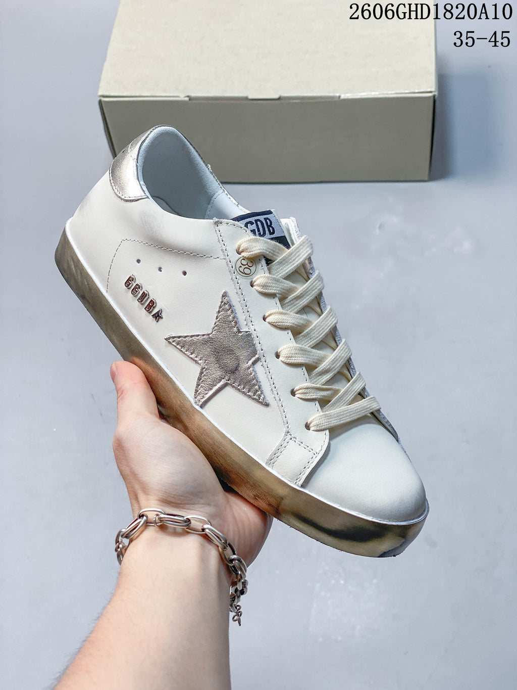 Angled view of the white low-top sneaker with a silver star appliqué, metallic heel tab and distressed-look sole.