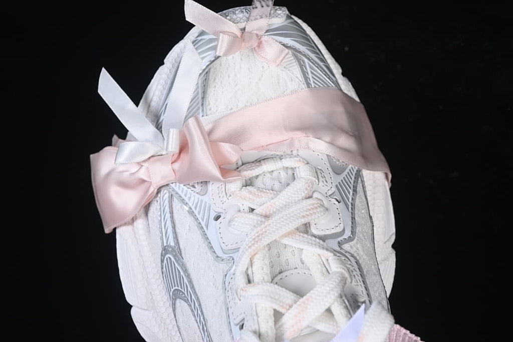 Top view of the sneaker with wide pink ribbon accents across the laces.