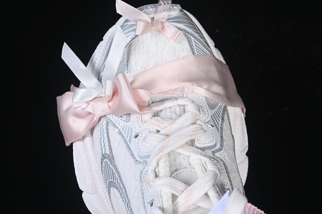 Top view of the sneaker with wide pink ribbon accents across the laces.