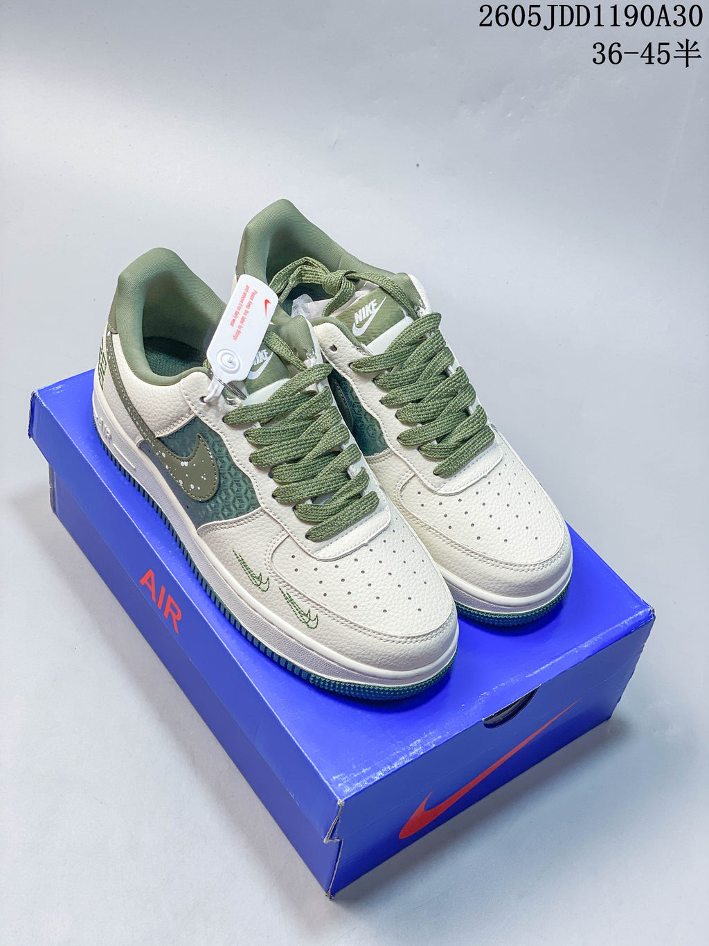 Pair of white low-top sneakers with green laces, green patterned side panels, and green accents