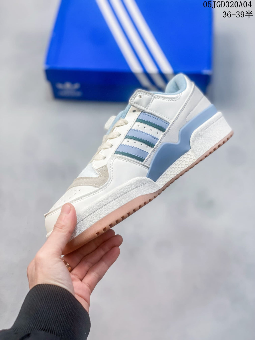 Side view of the white sneaker with blue and teal stripes and an ankle strap