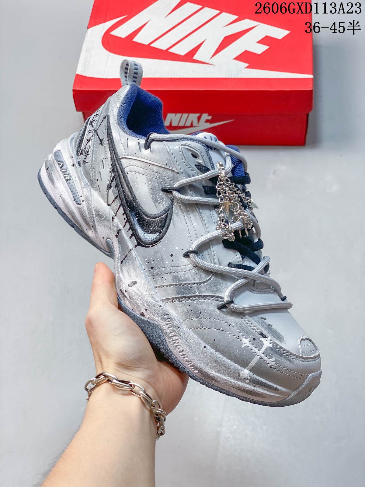 Side view of a silver Nike Air Monarch sneaker with navy detailing and layered panels