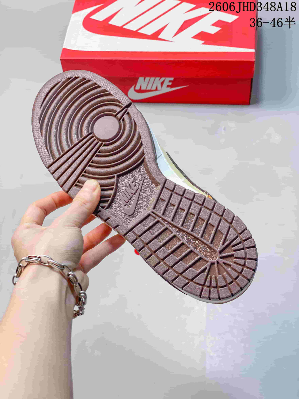 Brown outsole of the Nike SB Dunk Low sneaker beside a red Nike shoe box