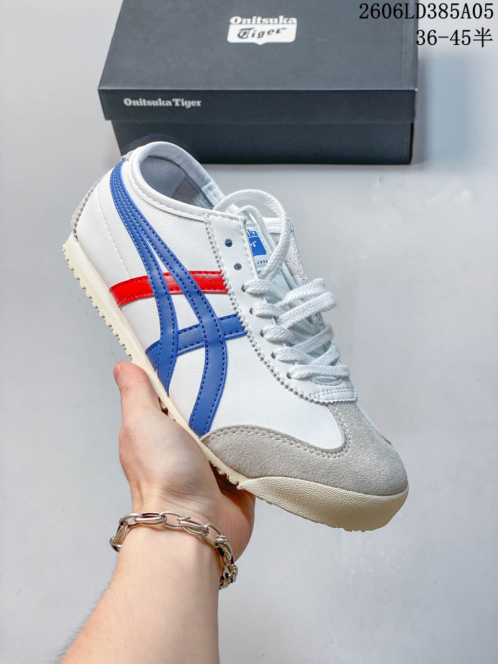 Angled side view of the white, blue and red Onitsuka Tiger Mexico 66 Deluxe sneaker.