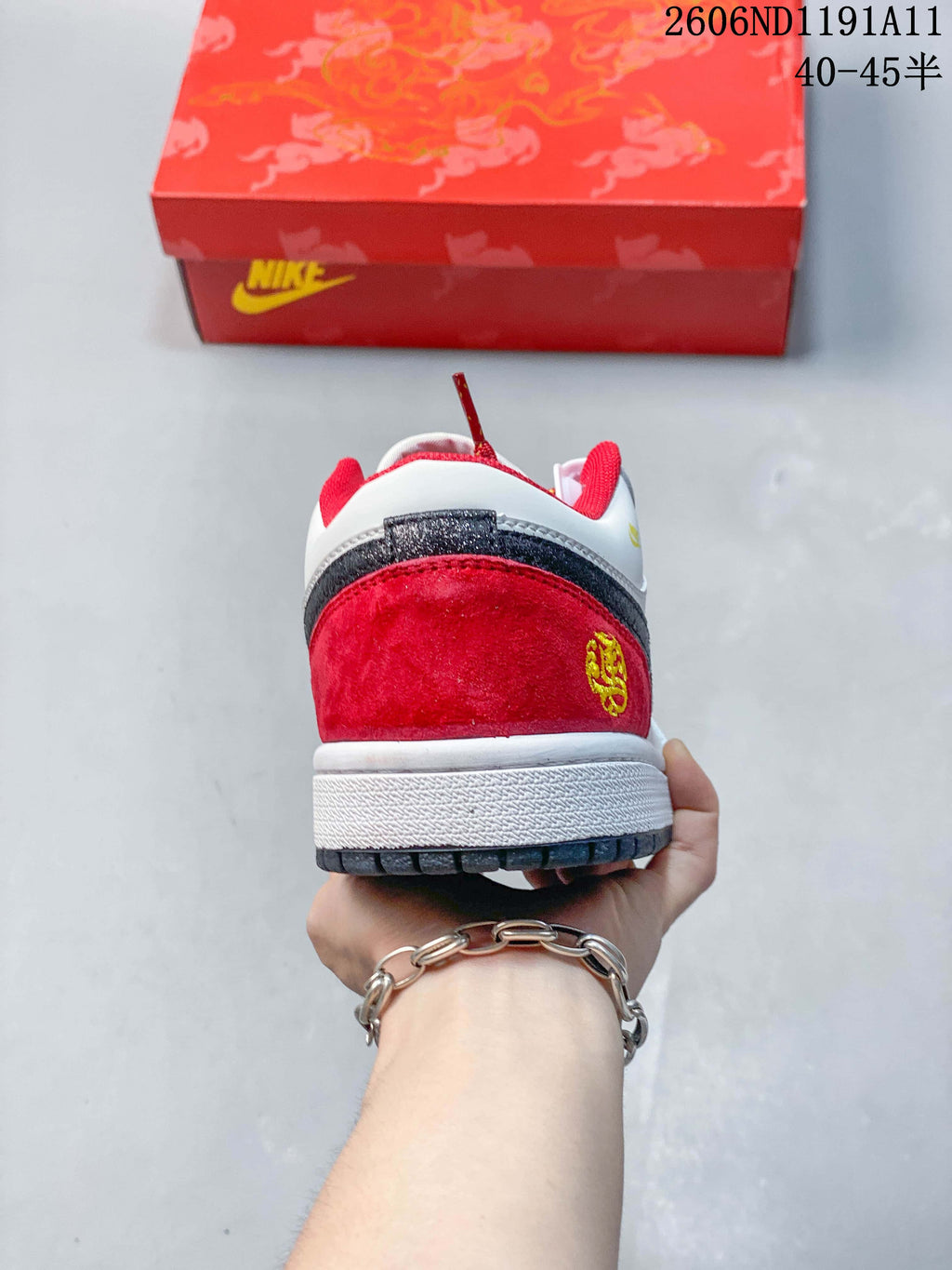 Rear view of the white and red low-top sneaker, showing a dark heel overlay, red heel panel, and decorative emblem.