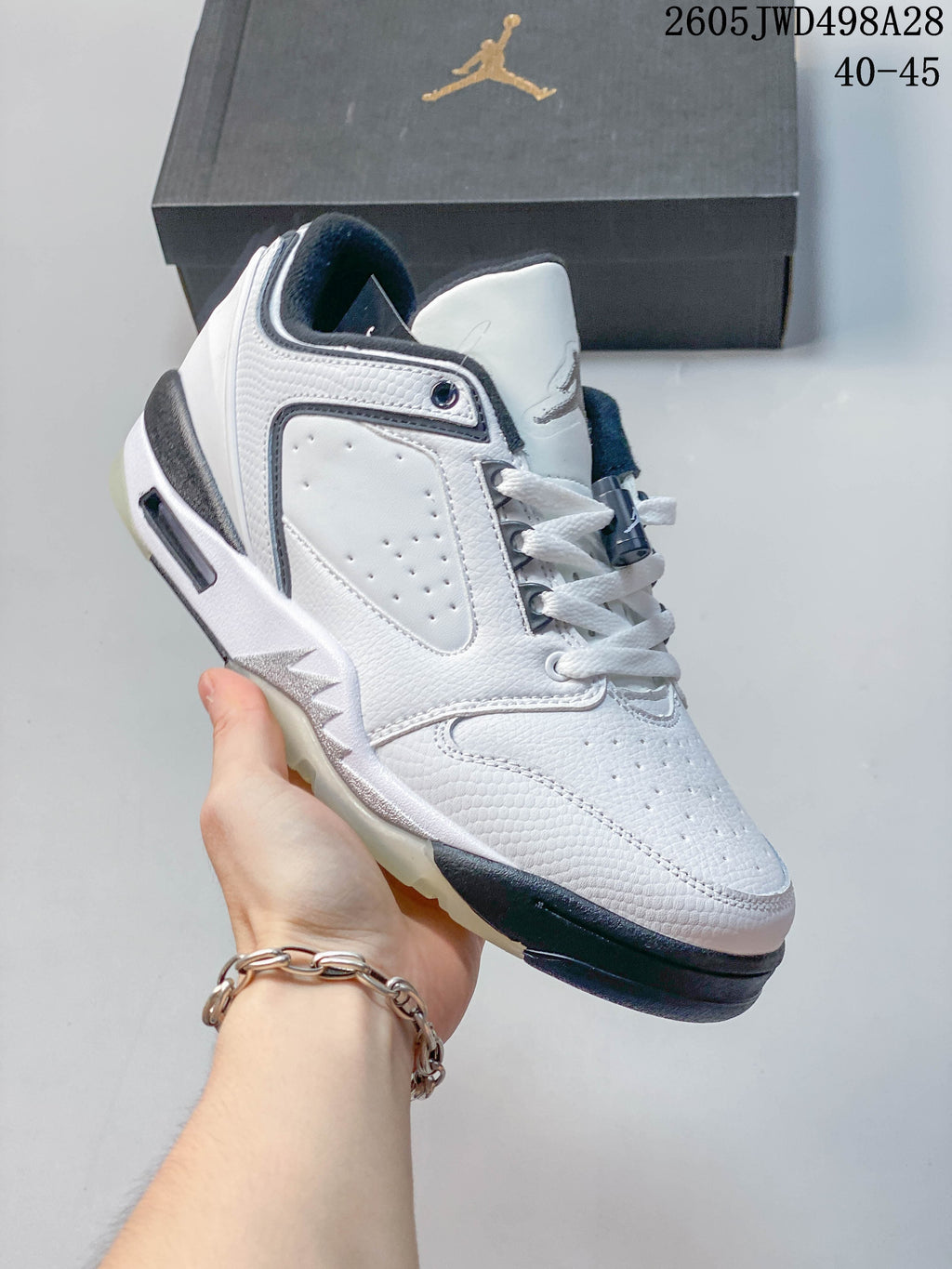 Angled view of the white low-cut sneaker with gray detailing and a dark outsole.