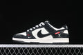 Side view of black and white low-top sneakers with patterned panels and red accents