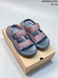 Pair of brown and dark gray open-toe sandals with adjustable straps, shown on a box.