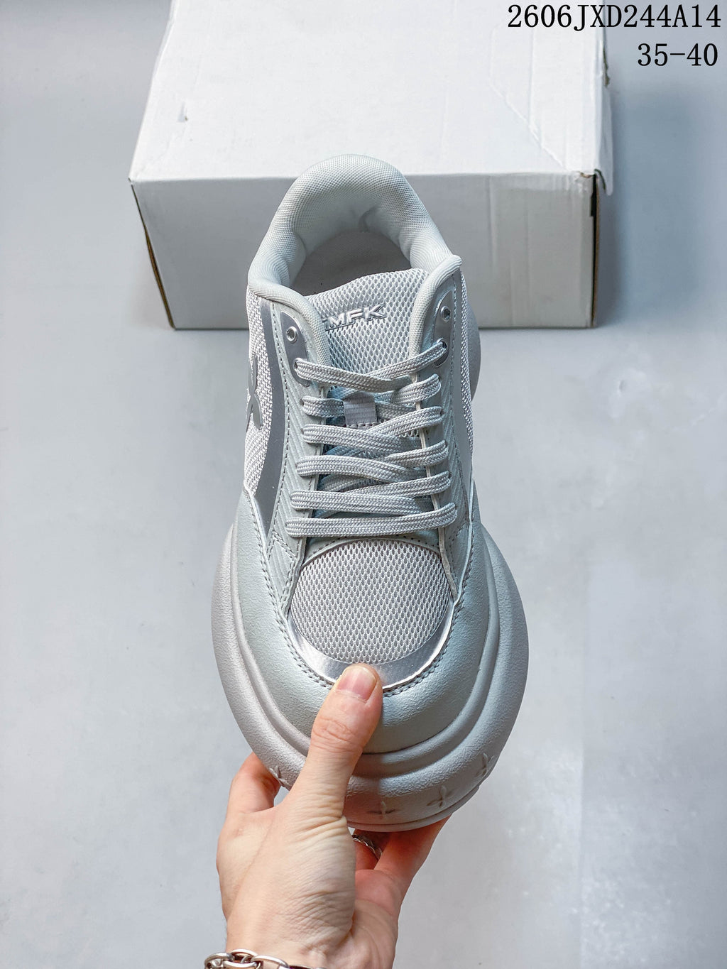 Front view of a lace-up sneaker with mesh-look panels and a rounded toe