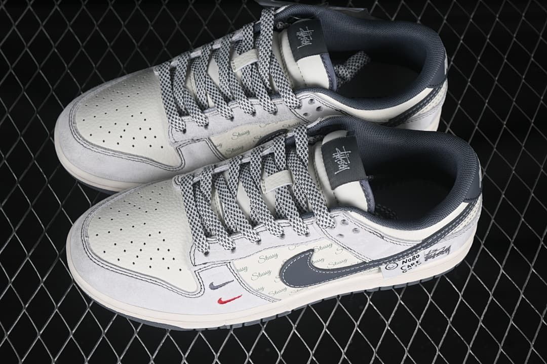 Top view of a pair of light grey Nike SB Dunk Low sneakers with patterned laces and graphic side details