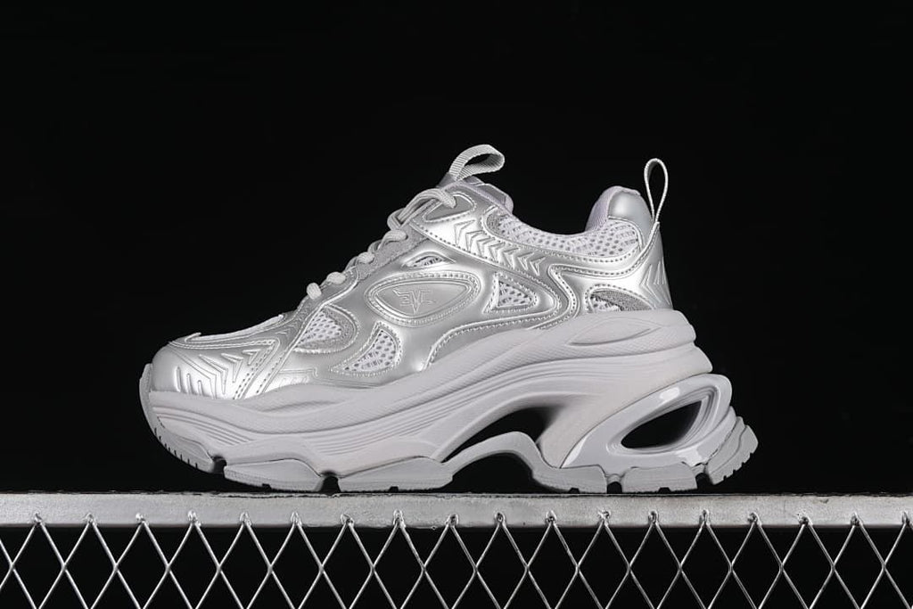 Side view of a silver lace-up sneaker with a sculpted chunky sole.